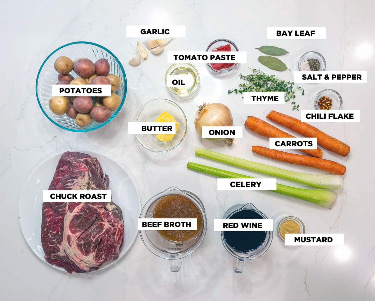 Ingredients needed for Braised Beef, featuring: a chuck roast, beef broth, red wine, mustard, tomato paste, butter, oil, garlic, onion, celery, carrots, potatoes, thyme, bay leaves, salt & pepper, and chili flakes. 