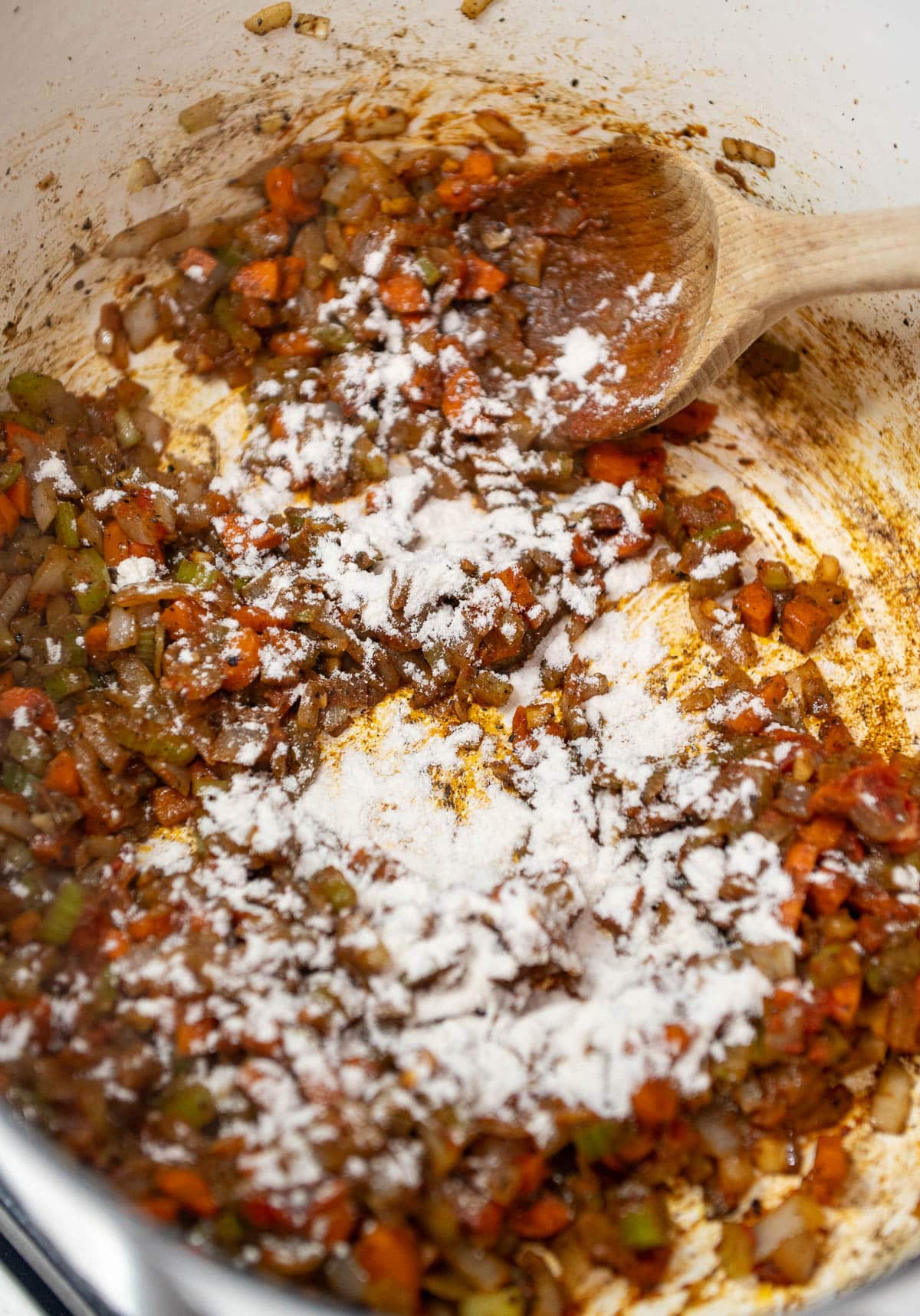 Mirepoix sautéing in a dutch oven with flour sprinkled on top.