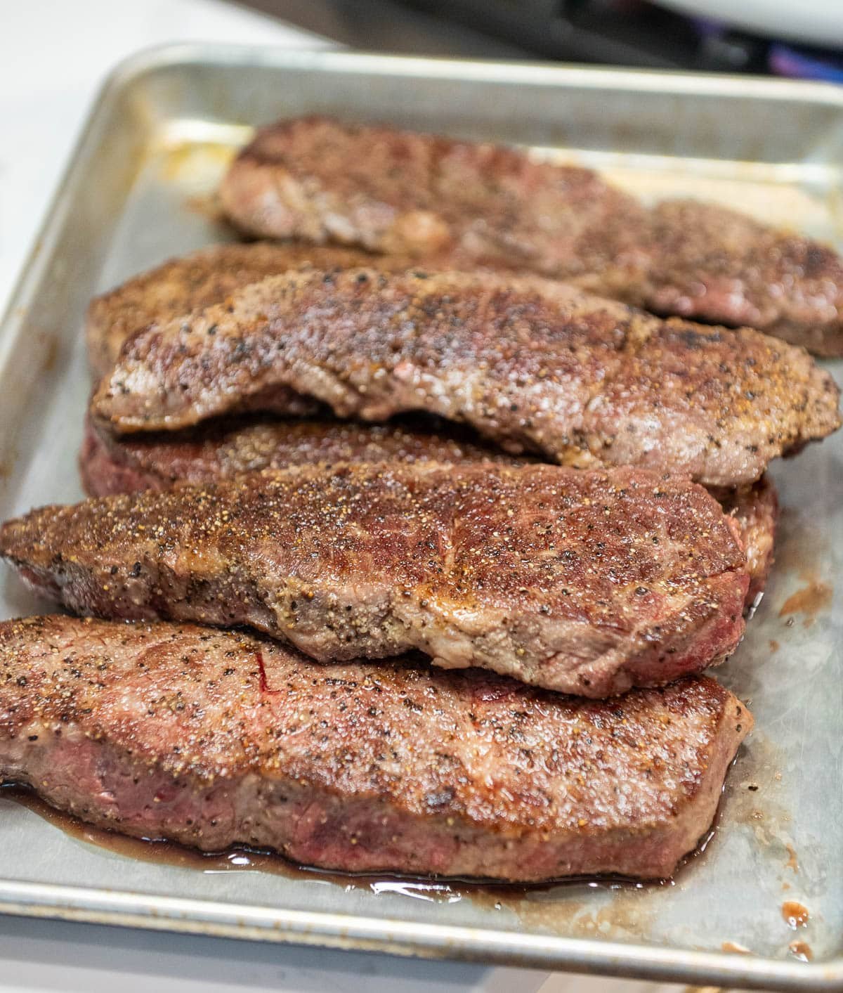 Fully-cooked, boneless beef short ribs set aside on a baking sheet. 