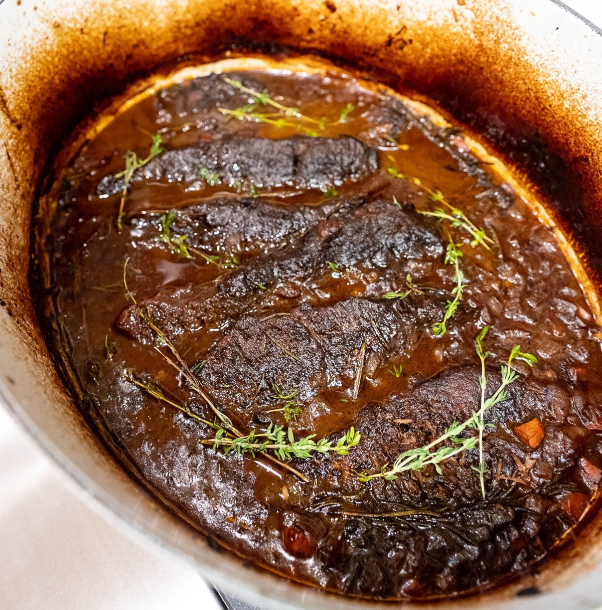 The finished braised beef short ribs dish in a dutch oven, ready to serve. 