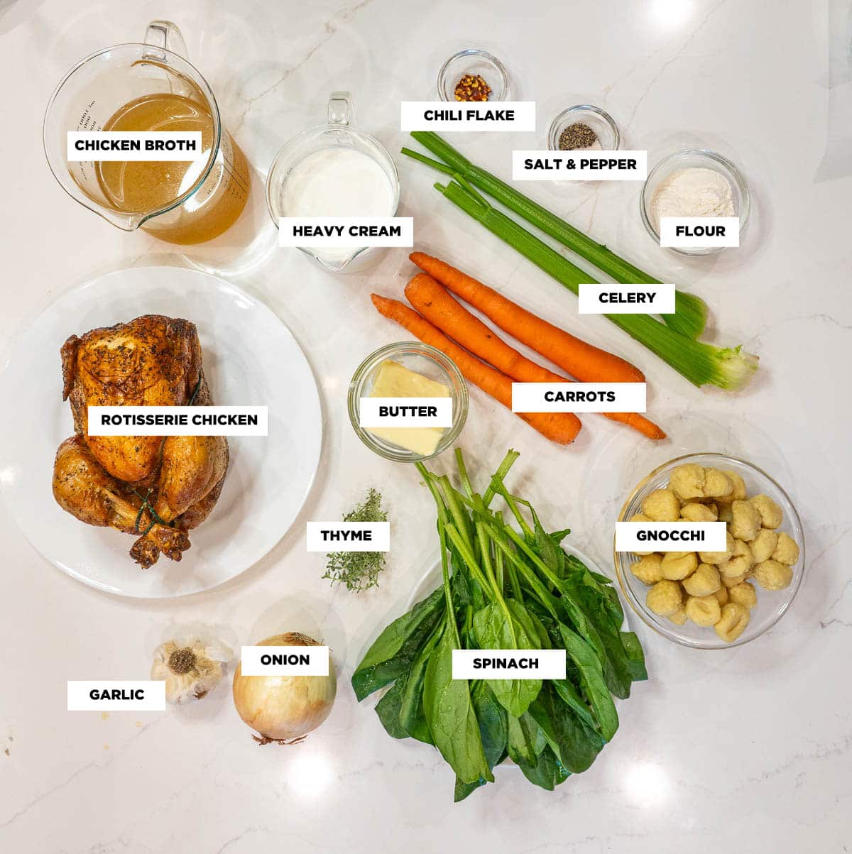 Ingredient shot for Chicken Gnocchi Soup, featuring: a rotisserie chicken, chicken broth, heavy cream, red pepper flakes, salt & pepper, flour, butter, carrots, celery, onion, garlic, fresh thyme, spinach, and gnocchi.