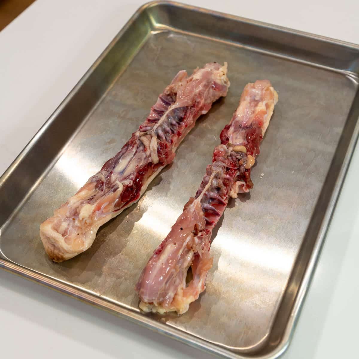 The spine from the chicken on a baking sheet.