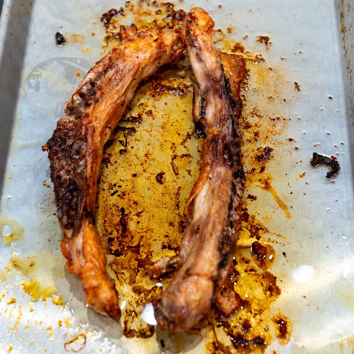 The spine from the chicken on a baking sheet, which has been roasted.