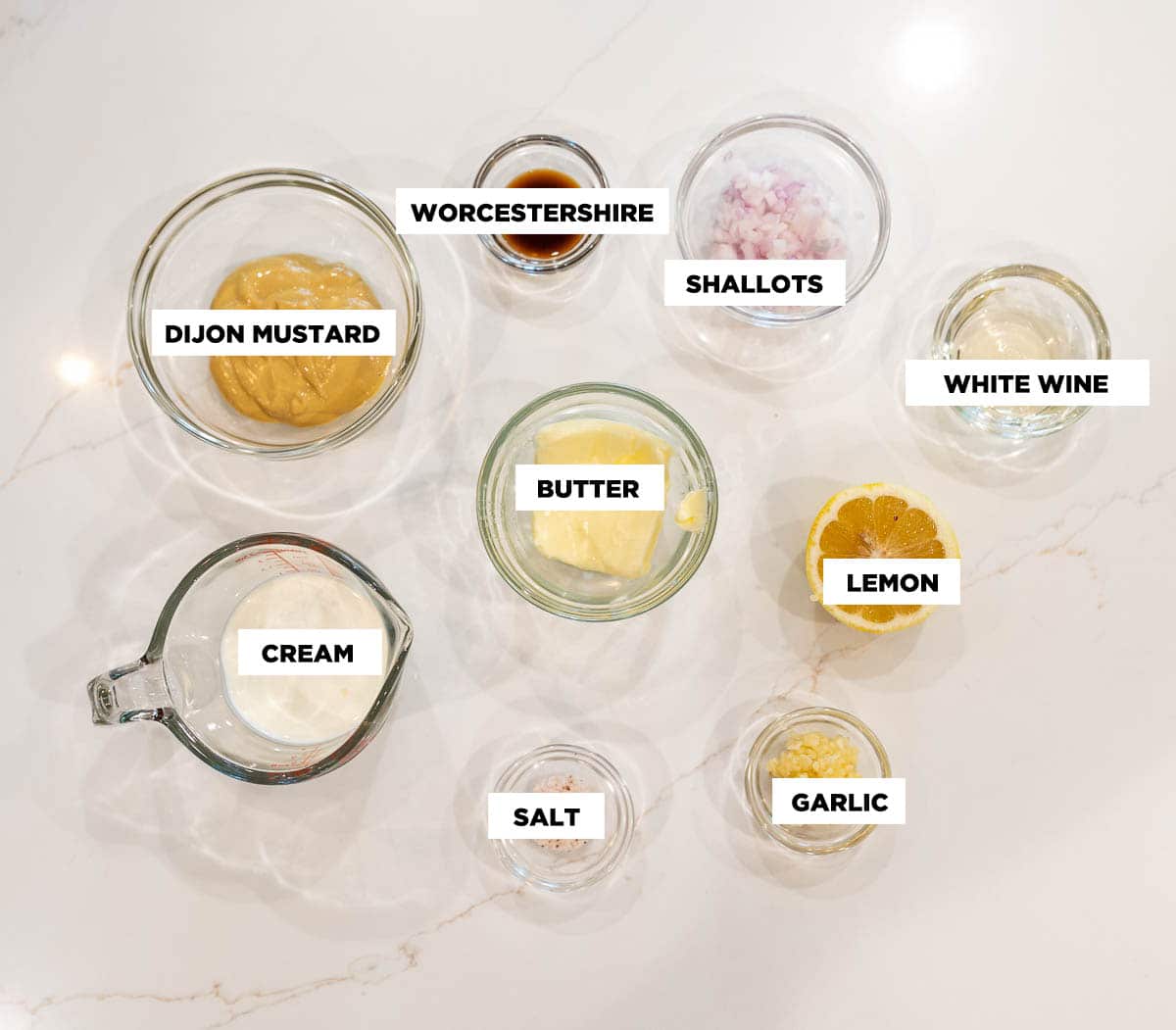 Ingredients for creamy Dijon sauce, featuring: Dijon mustard, Worcestershire sauce, finely chopped shallots, white wine, butter, a half a lemon, heavy cream, minced garlic, and salt.  