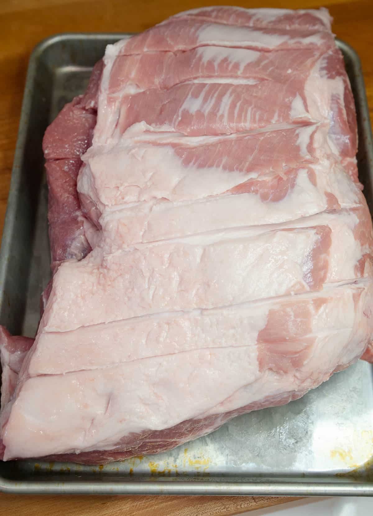 Raw pork shoulder on a baking sheet.