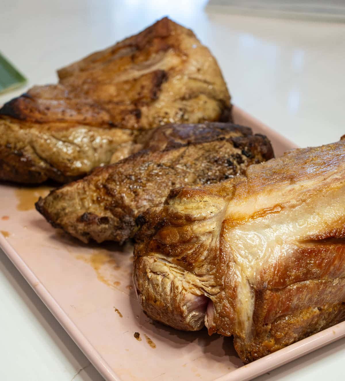 Pork shoulder roast seared to golden brown and cut into pieces on a tray.