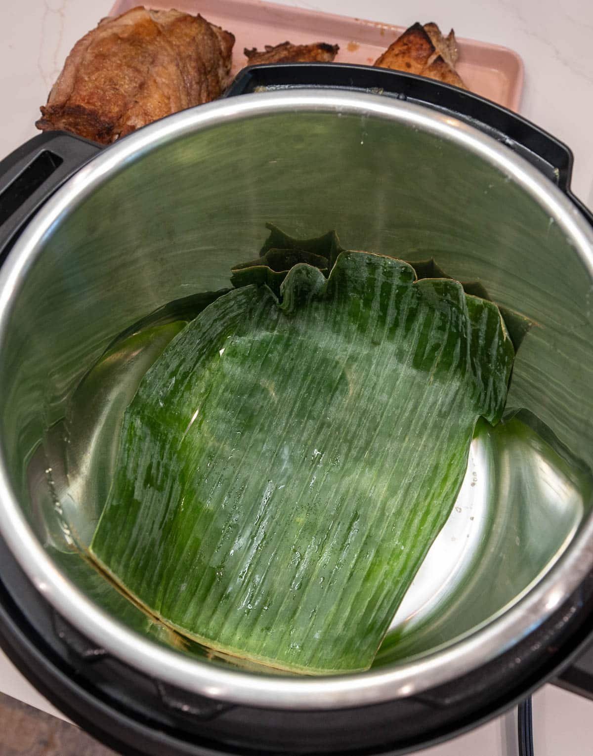 Instant pot with one banana leaf placed in the bottom.
