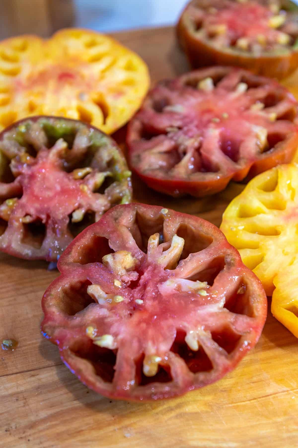 seeded heirloom tomatoes on a wooden cutting board