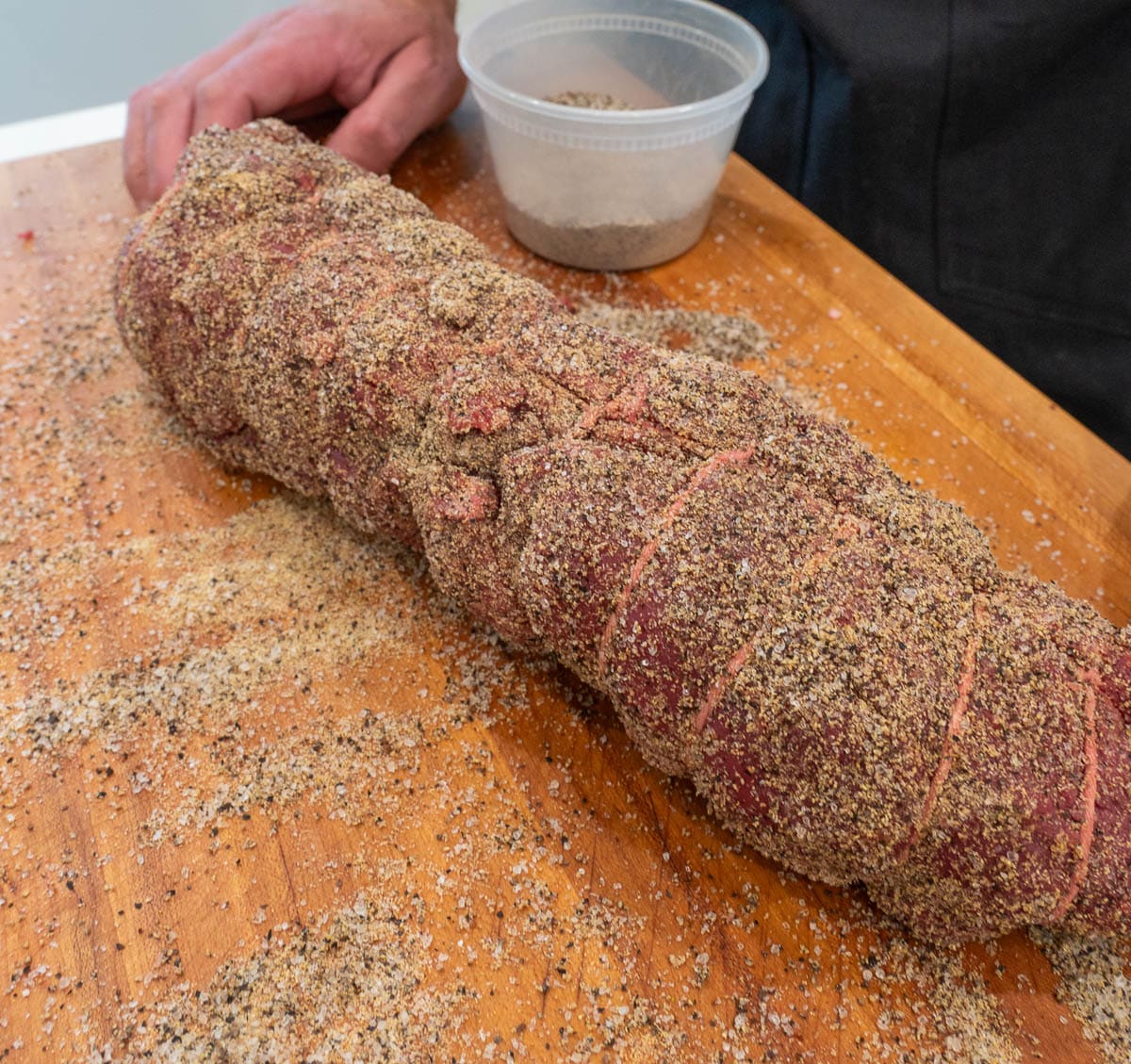 The whole, raw beef tenderloin, tied together with butcher's twine and seasoned on all sides.
