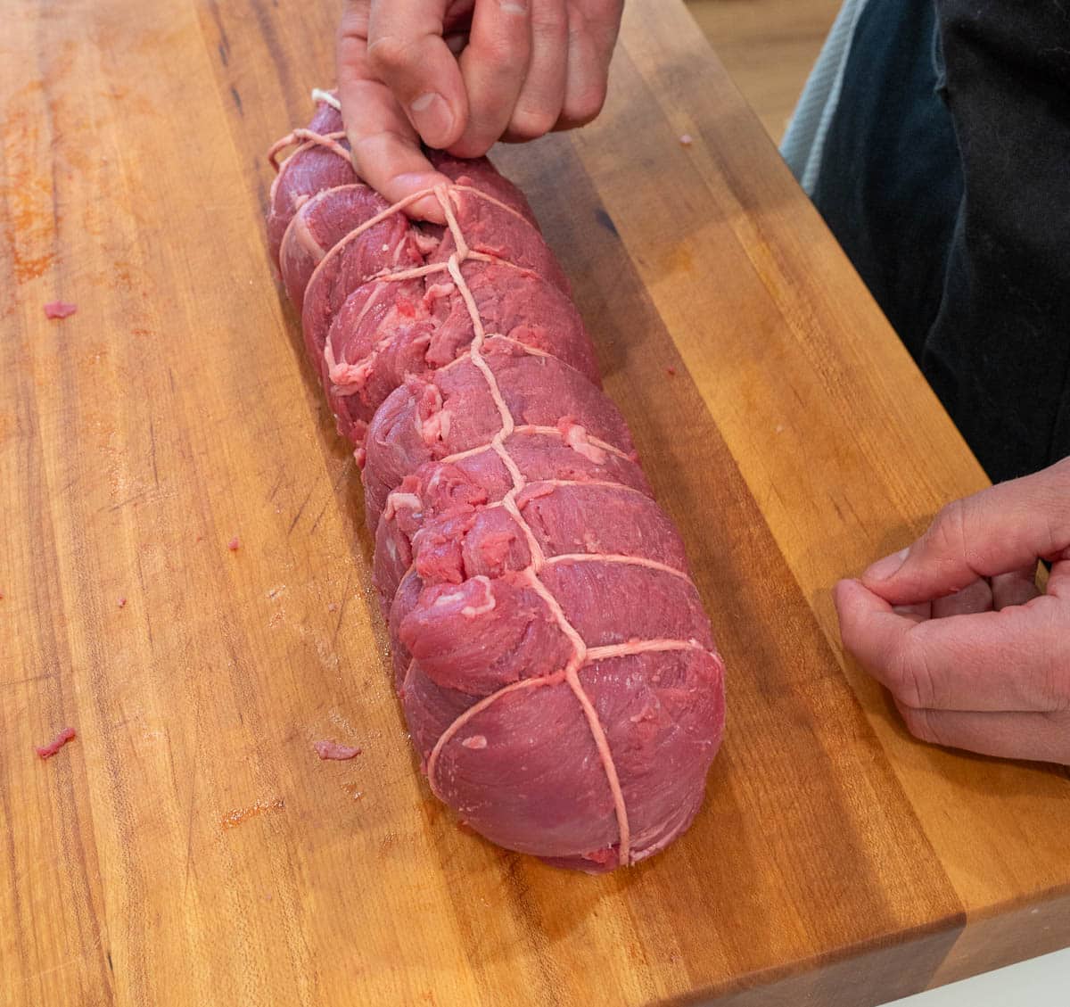 A whole, raw beef tenderloin tied together with butcher's twine.