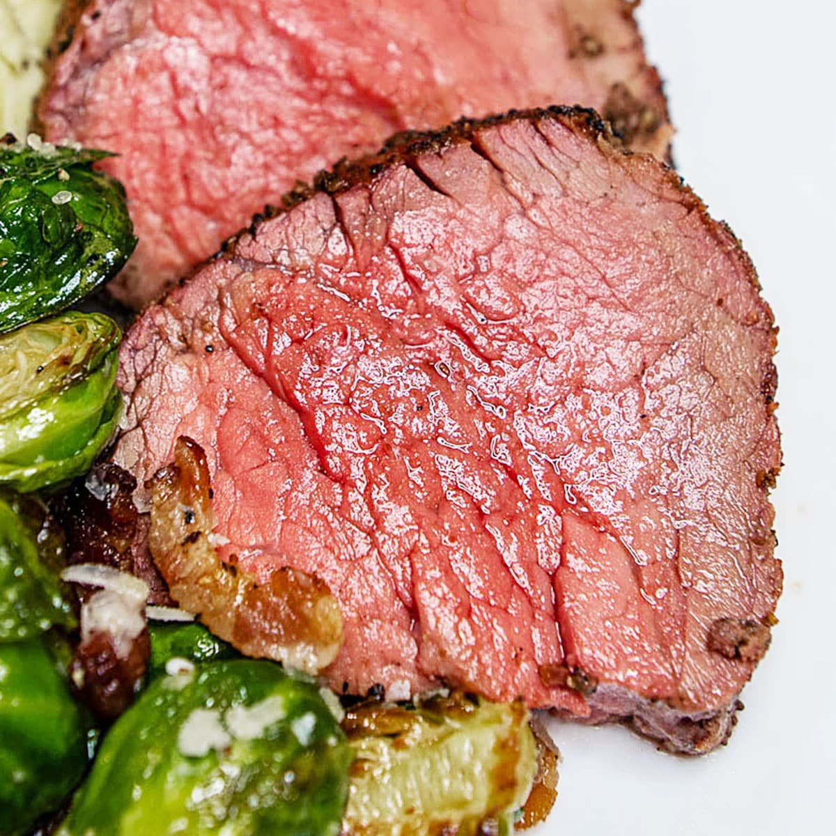 Smoked beef tenderloin sliced into medallions with a side of roasted Brussels sprouts. 