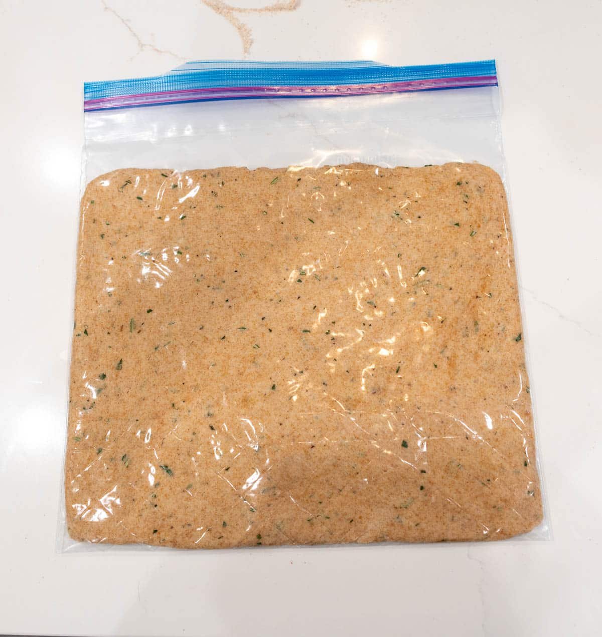 Dough inside a zip-top bag, flattened. 