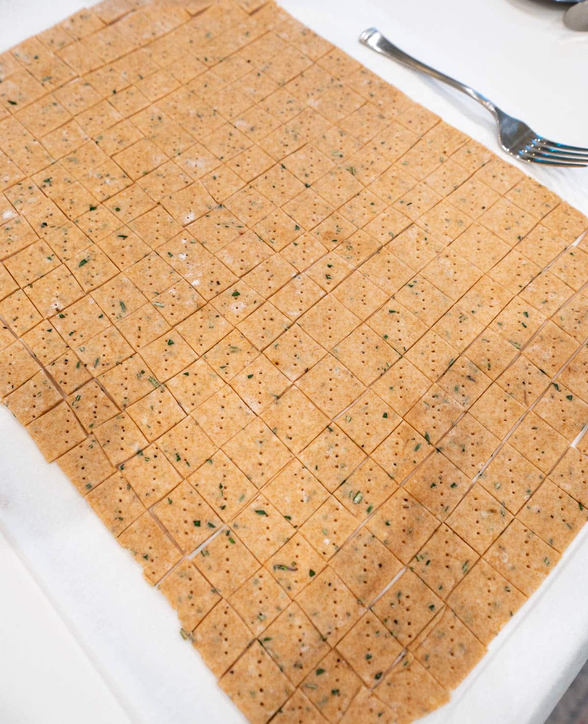 The small squares of dough are docked with a fork. 