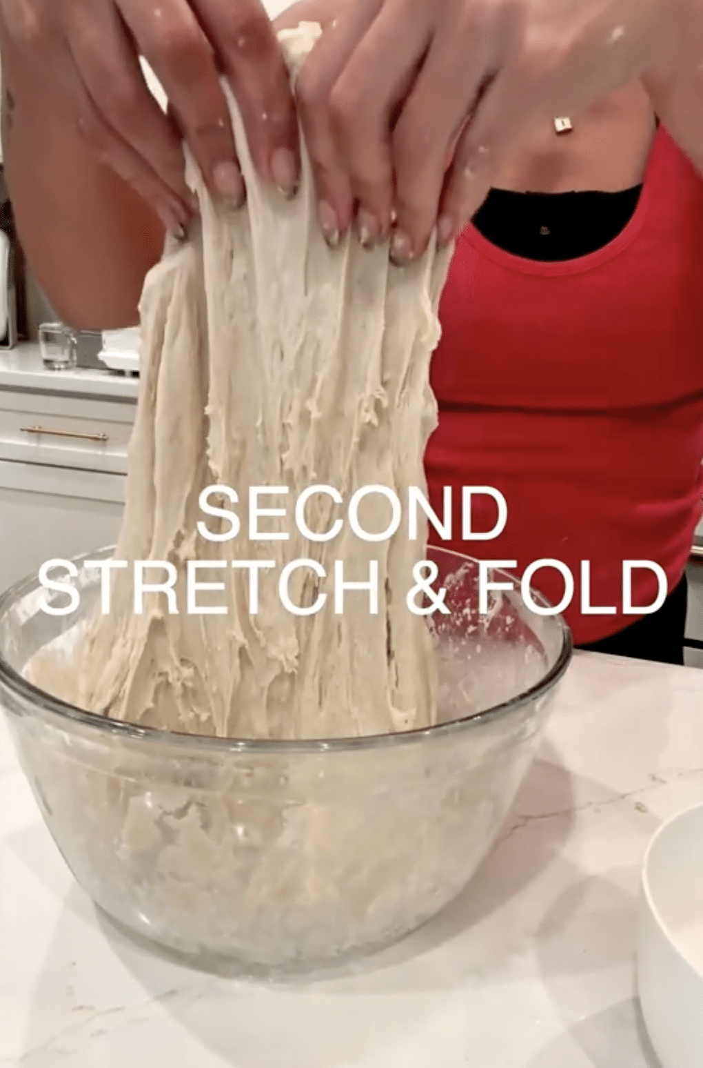 Stretching sourdough dough in a clear bowl.