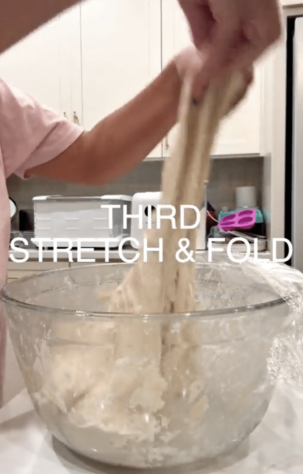 Stretching dough in a clear bowl.