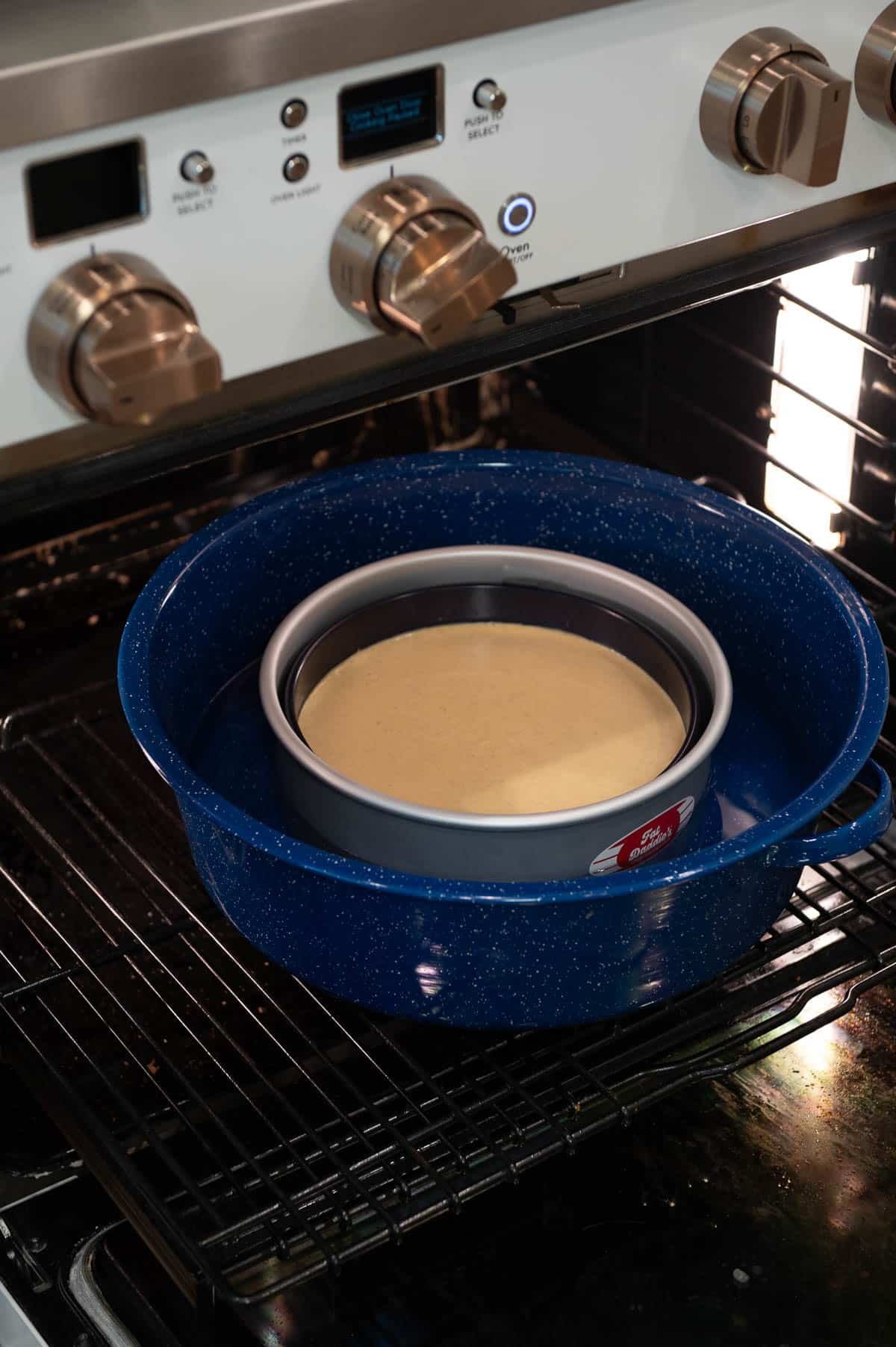 Spring-form pan with the cheesecake filling in it, placed inside a larger pan.