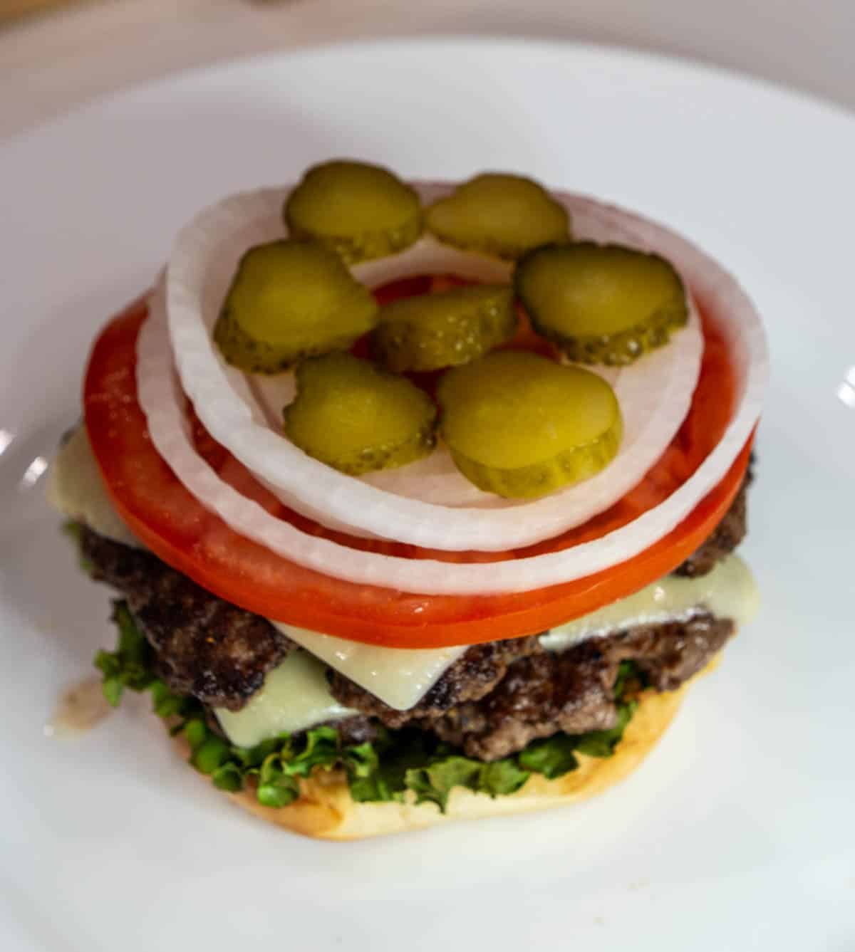 The smash burger on a bun and piled with toppings.