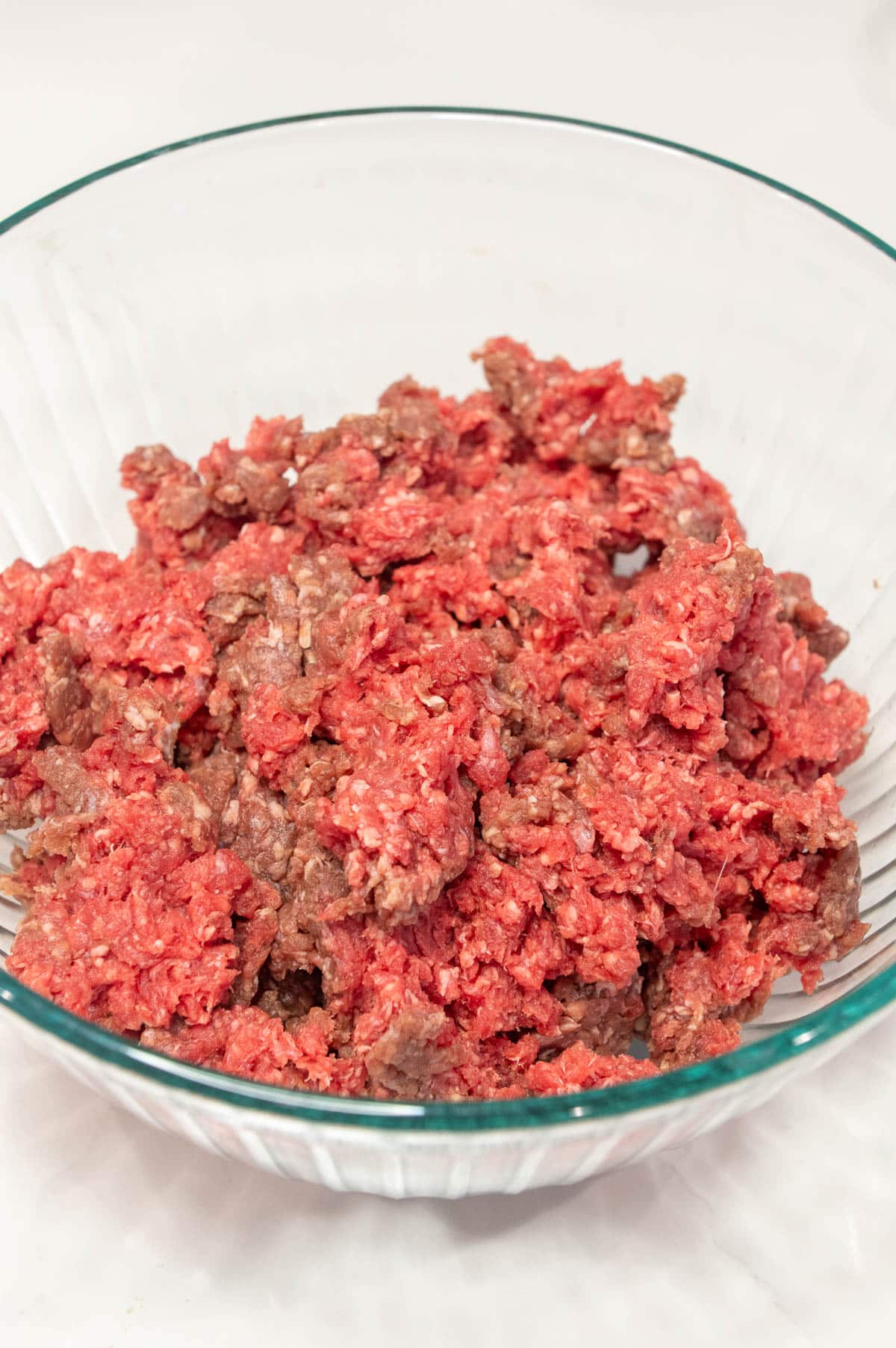 Large glass bowl of ground beef.