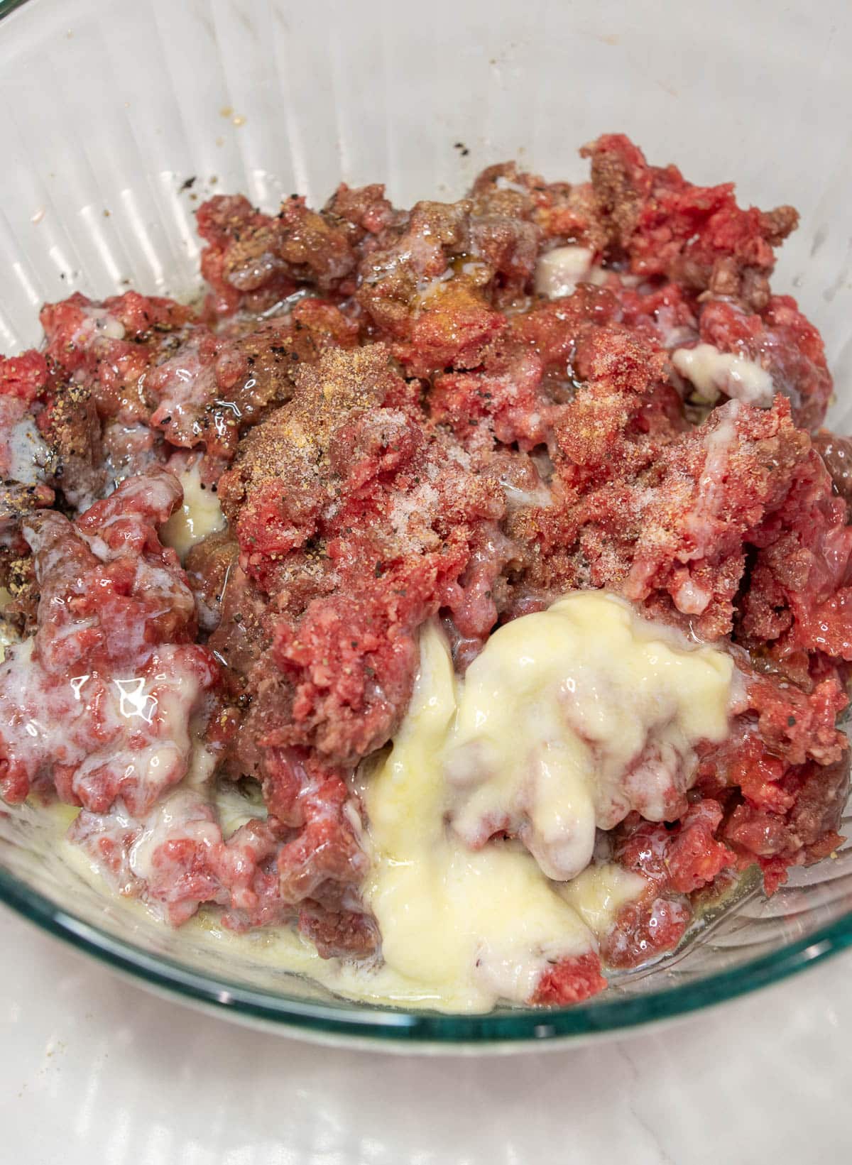 Large glass bowl of ground beef and remaining ingredients.