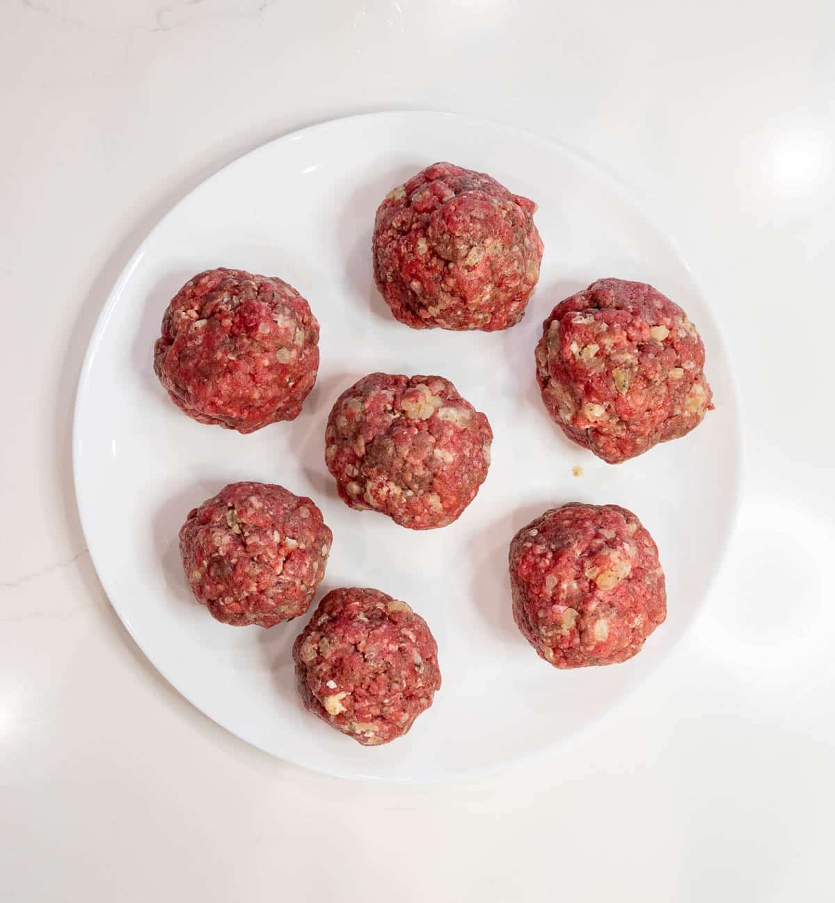 Ground beef formed into small balls on a plate.