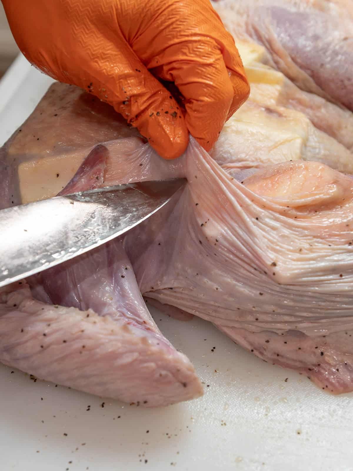 Another whole is being cut into the turkey skin.