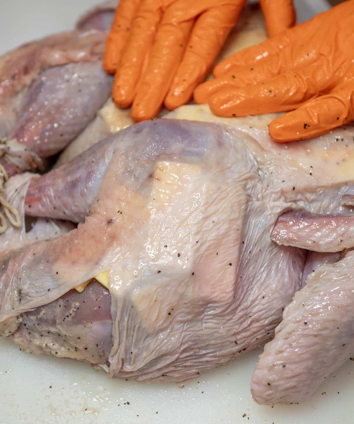 Gloved hands press down on the gold butter that is underneath the skin.