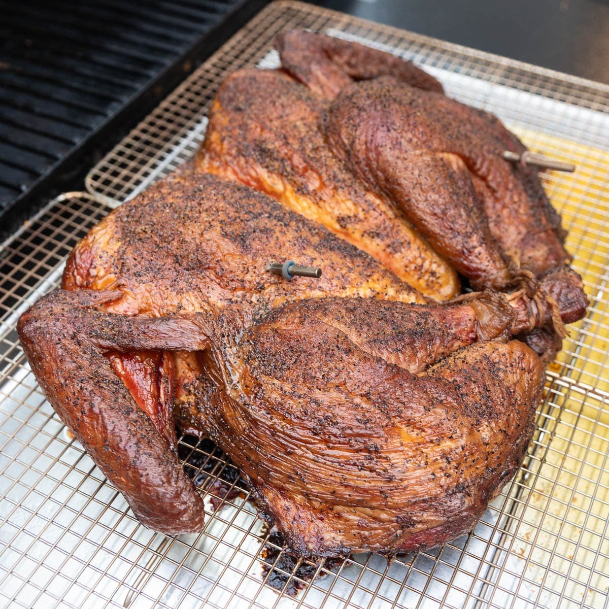 Instant-read thermometers have been inserted into the smoked turkey for the remainder of the cook time. 