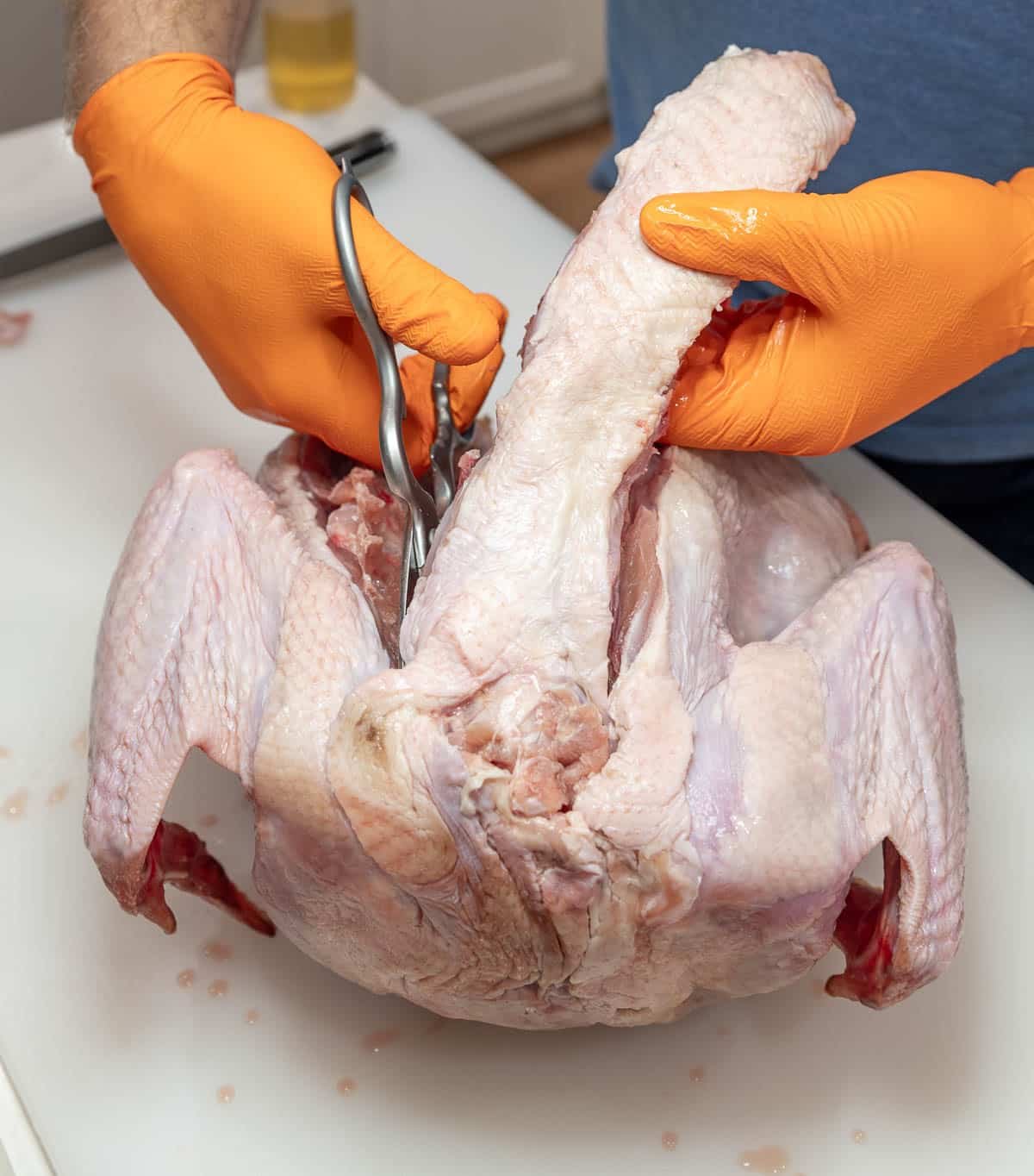 A raw turkey's neck is being cut out. 