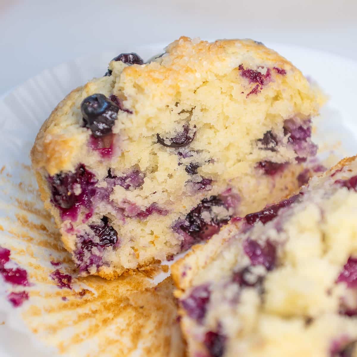 Closeup of sourdough discard blueberry muffin cut in half on a plate.
