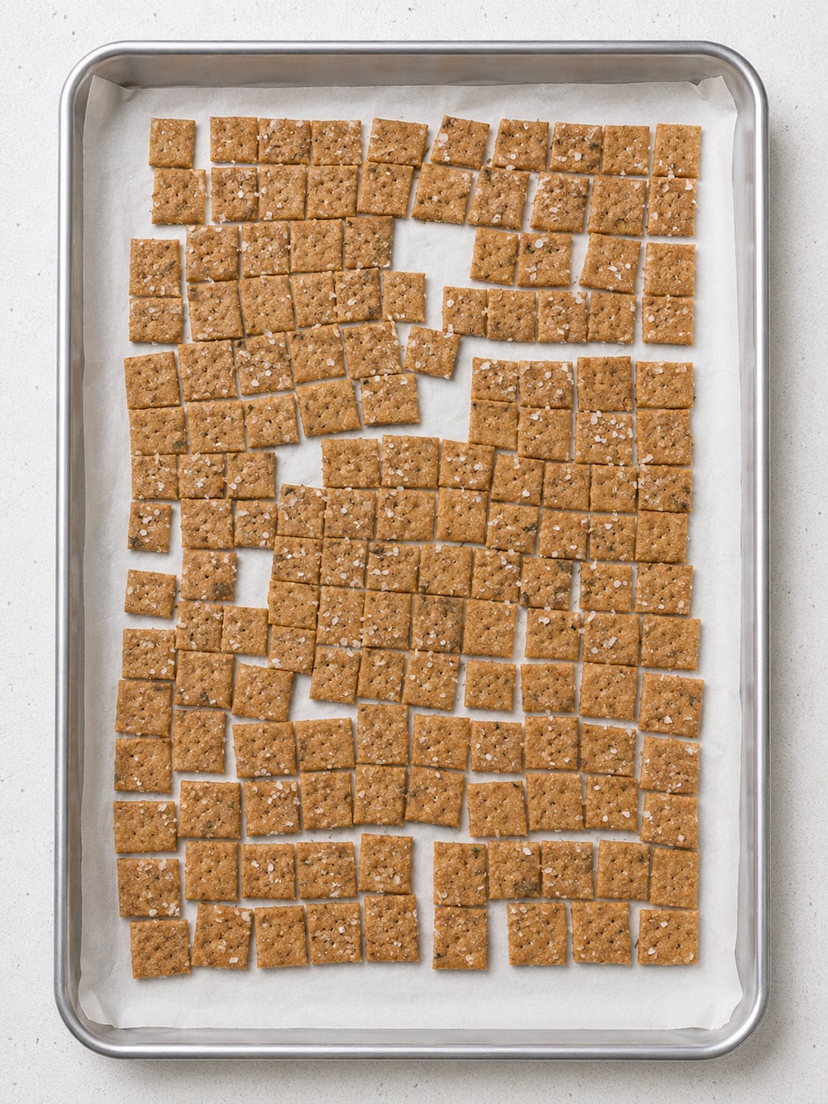 Closeup of sourdough discard crackers baked on a sheetpan with parchment paper.