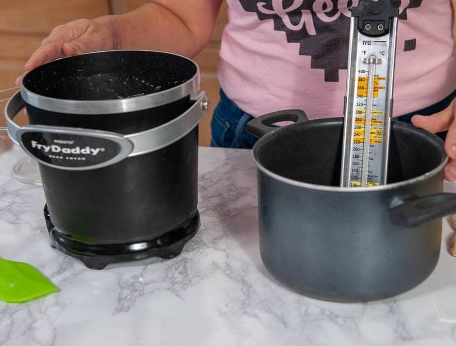 A photo of a Fry Daddy deep-fryer and a large pot with a kitchen thermometer clipped onto the side.