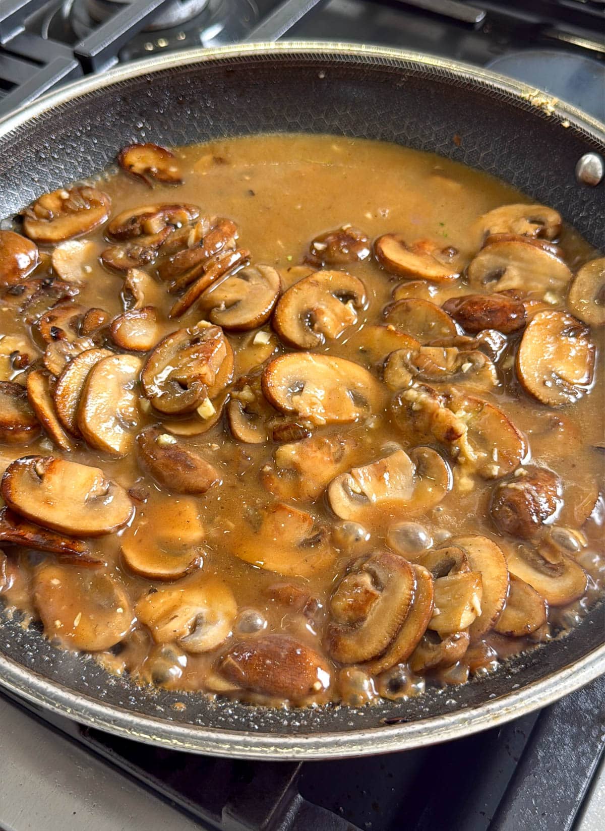 close up of mushrooms and chicken broth in a pan
