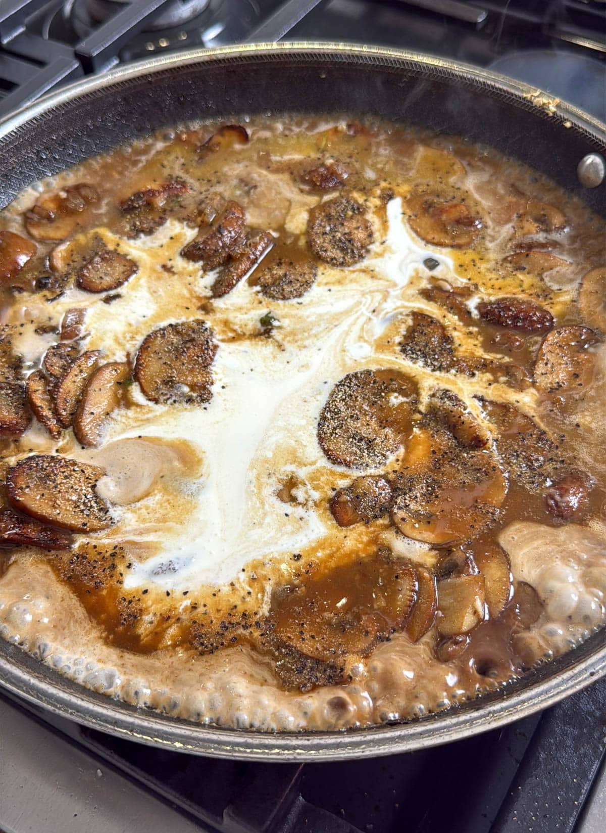 close up of mushrooms and cream sauce cooking in a pan