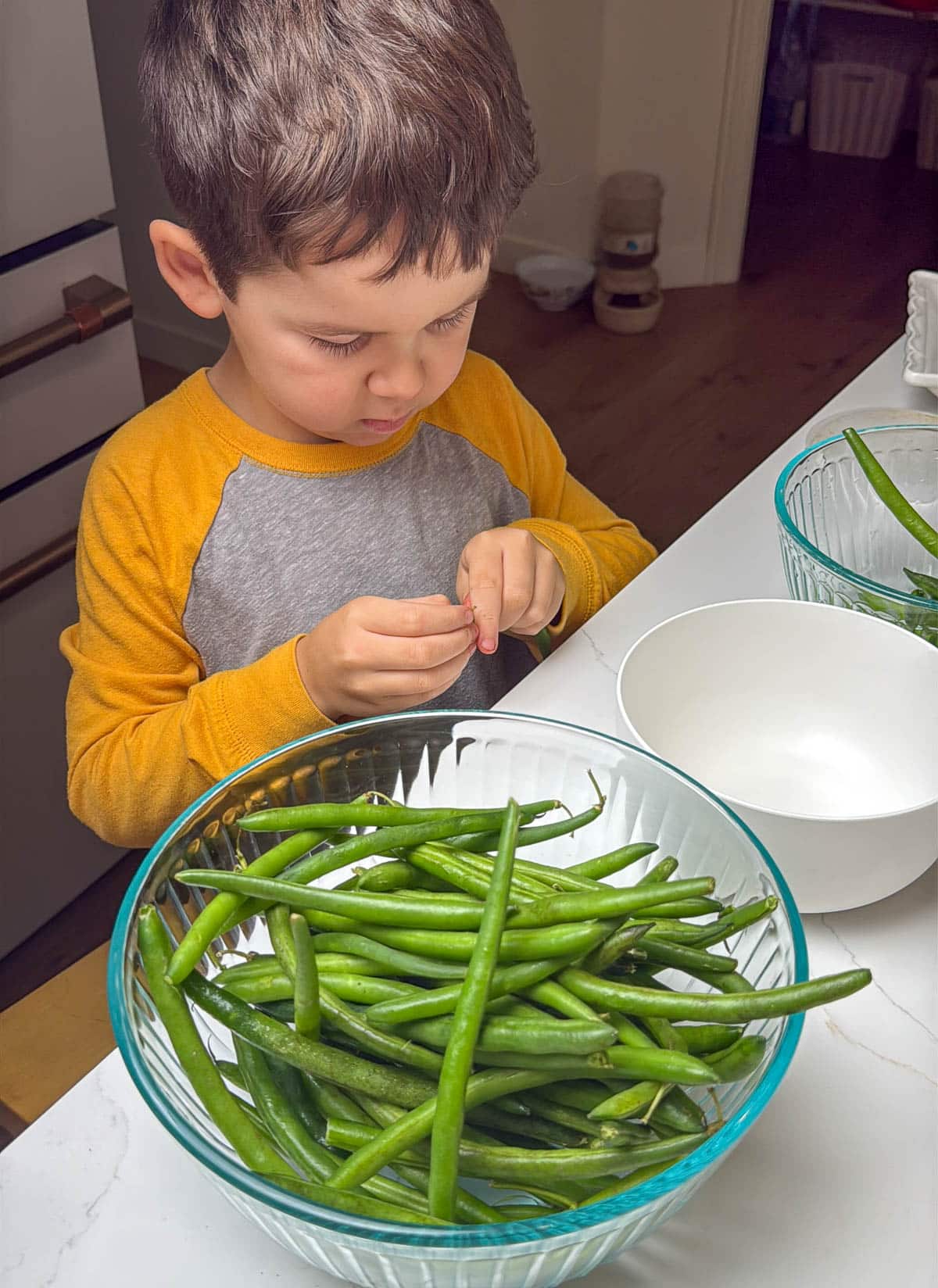 a boy preparing a bowl of fresh green beans