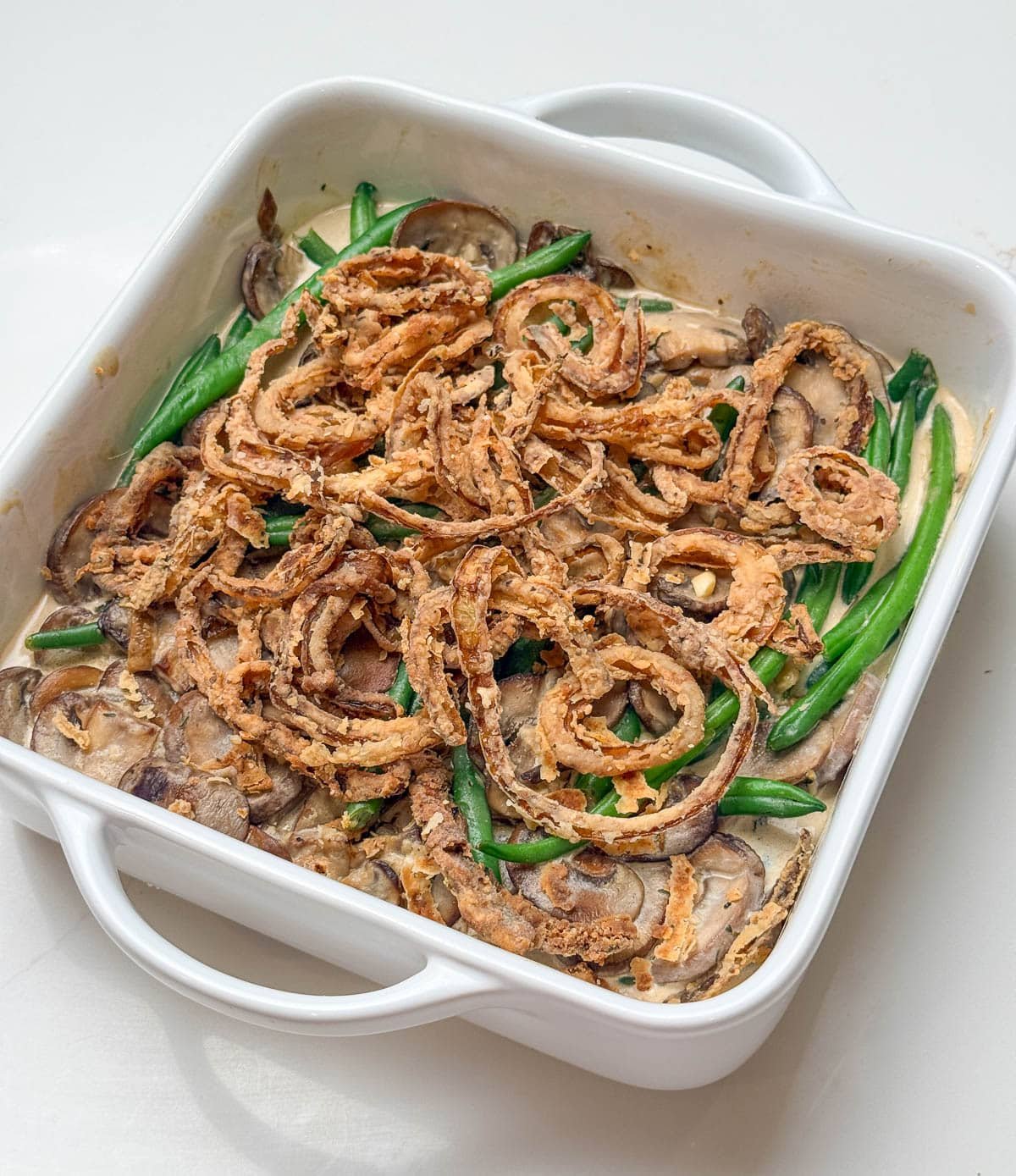 close up of finished green bean casserole in a square white casserole dish