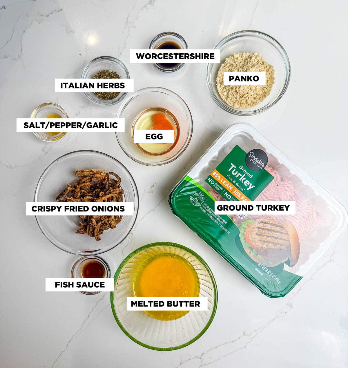Ingredient shot for ground turkey meatballs, featuring: ground turkey, Panko, Worcestershire sauce, egg, Italian herbs, salt/pepper/garlic seasoning, crispy fried onions, fish sauce, and melted butter.