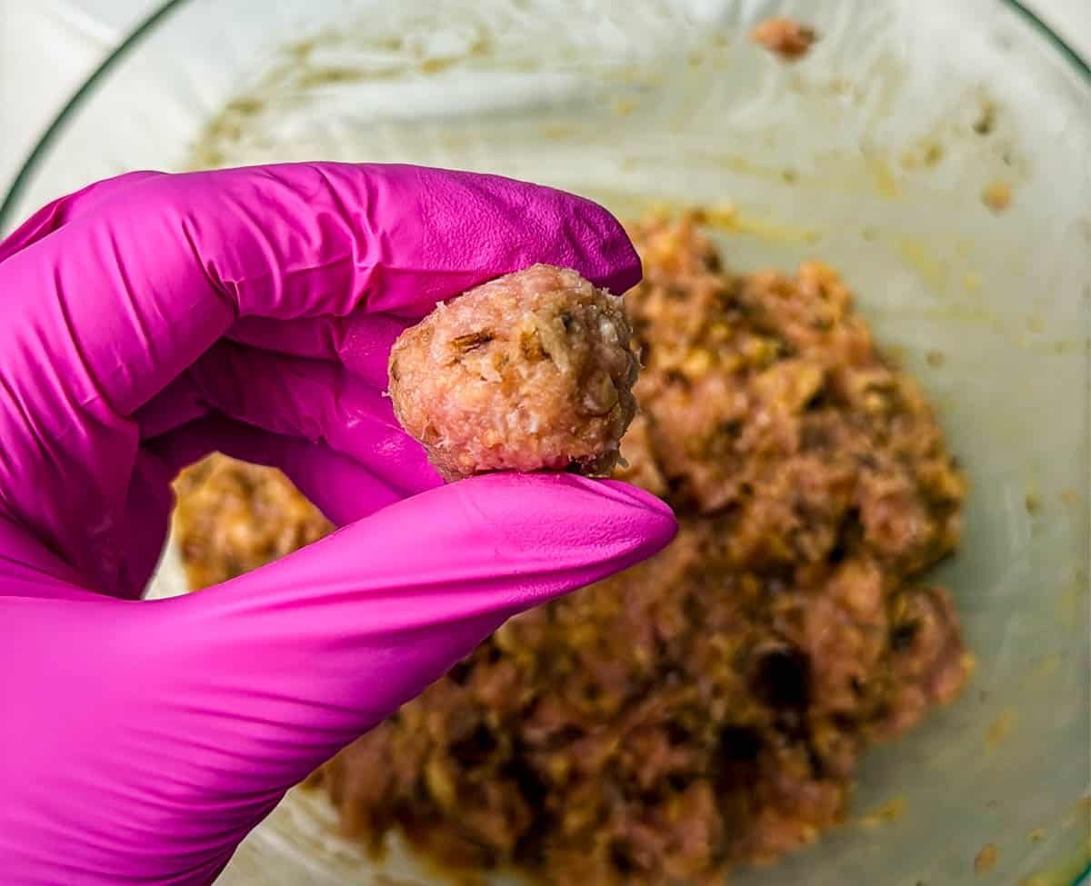 A close-up photo of a raw ground turkey meatball.