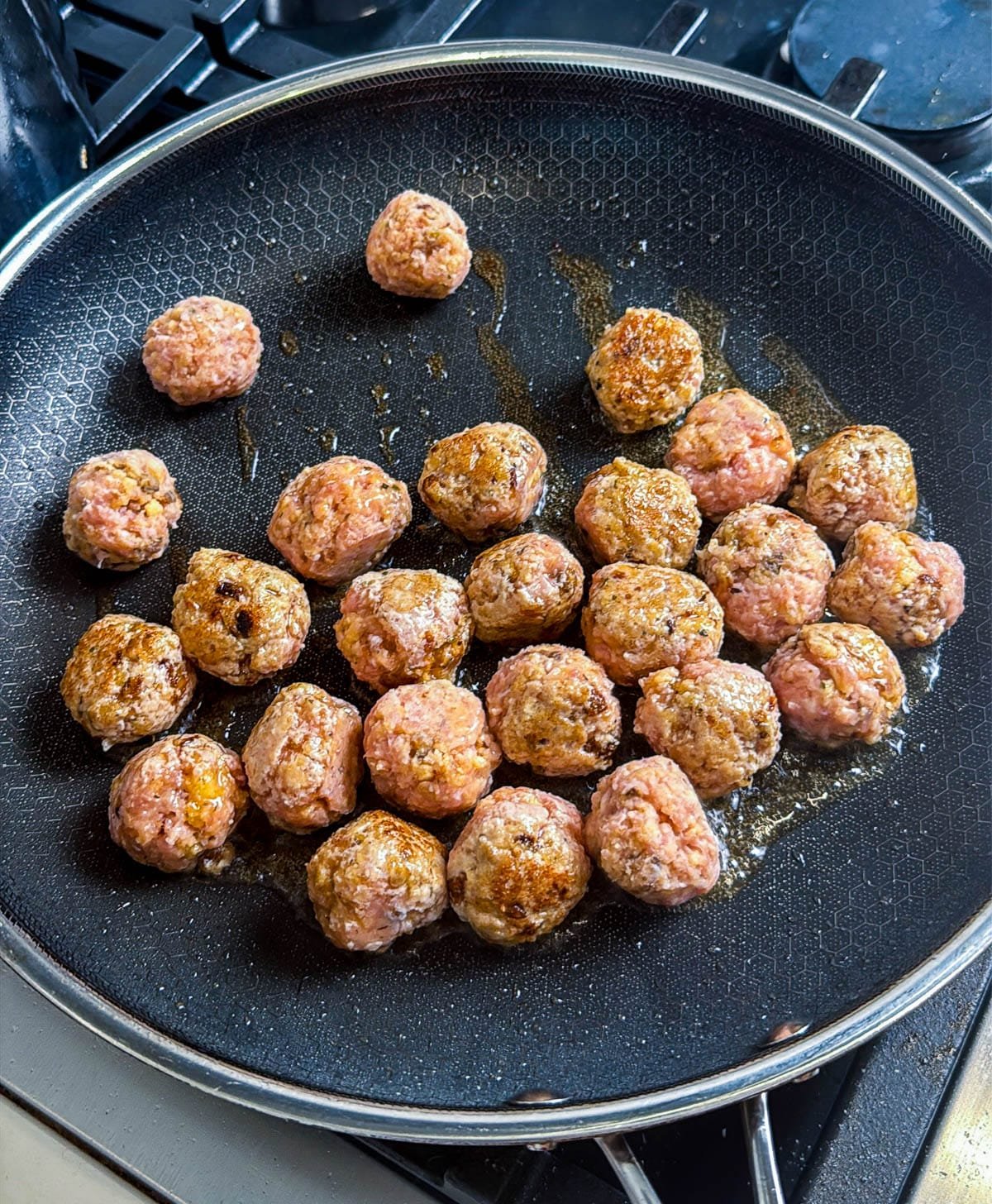 Raw meatballs in a large skillet.
