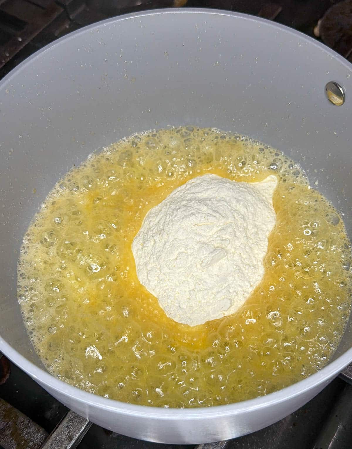 Flour is added to the butter in the saucepan. 