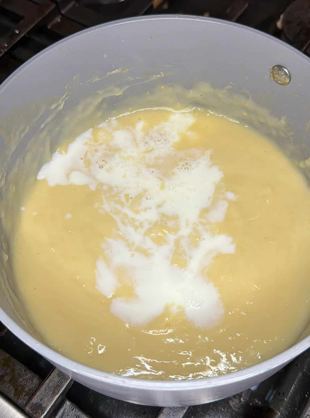 More milk is added slowly, a little at a time to create a smooth roux.