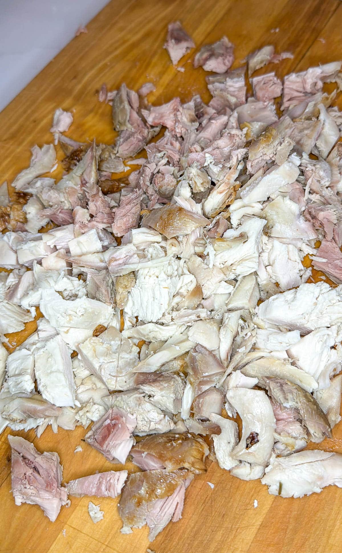 Chopped leftover turkey on a wooden cutting board.