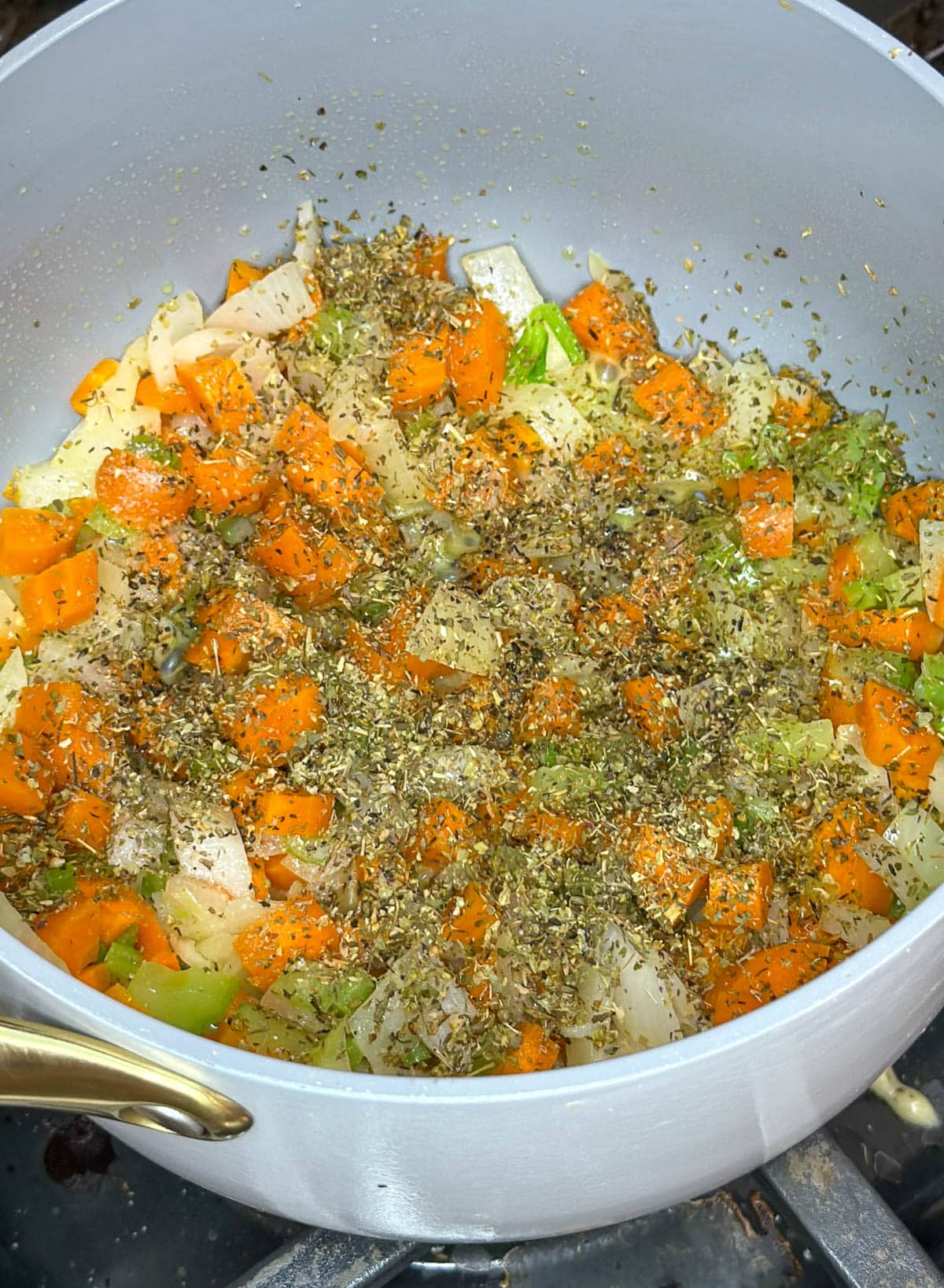 Chopped carrots, celery, and onion in saucepan with seasoning on top.