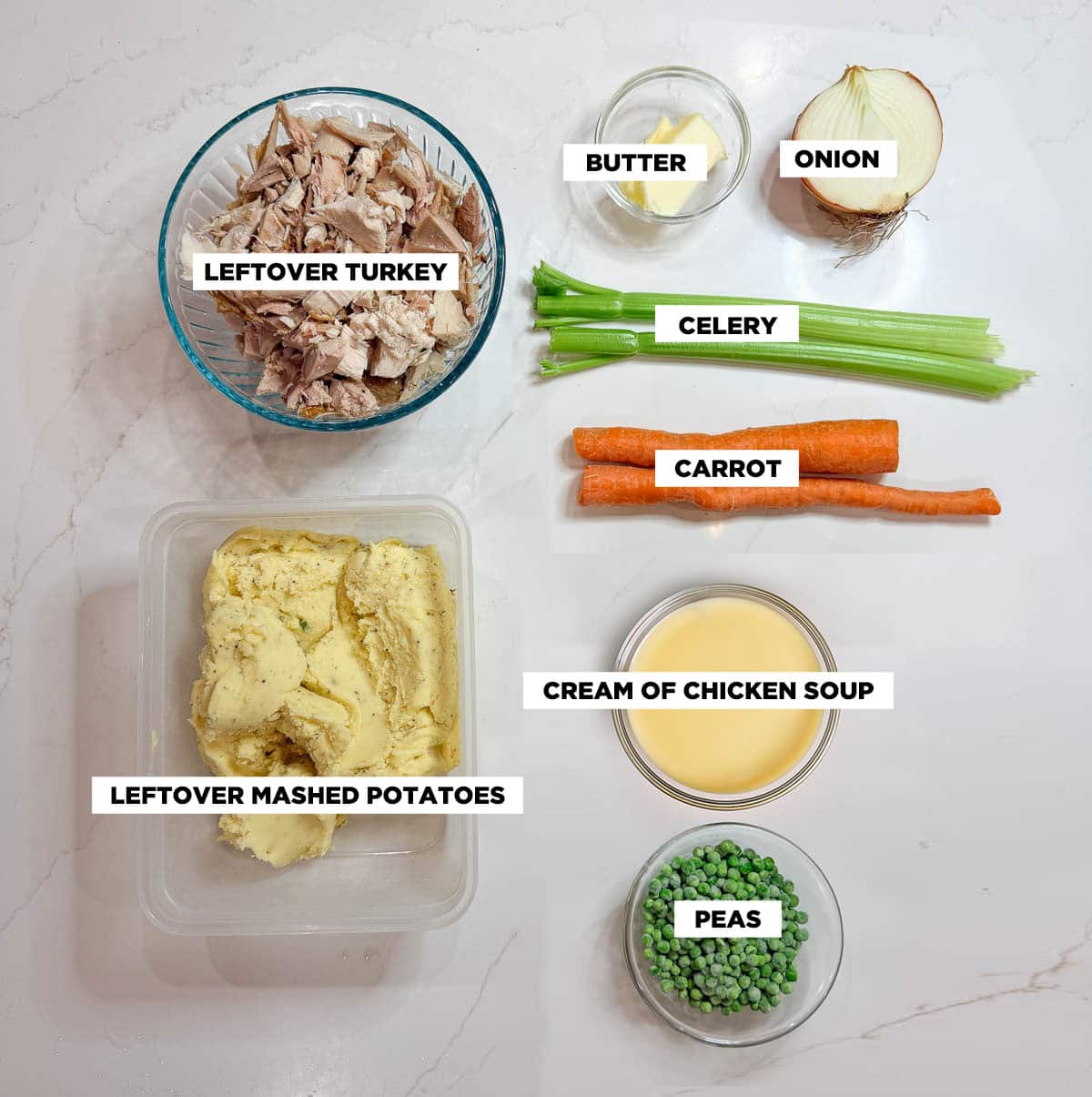 Ingredient shot for Leftover Thanksgiving Casserole, featuring: leftover turkey, leftover mashed potatoes, cream of chicken soup, butter, onion, celery, carrot, and frozen peas.