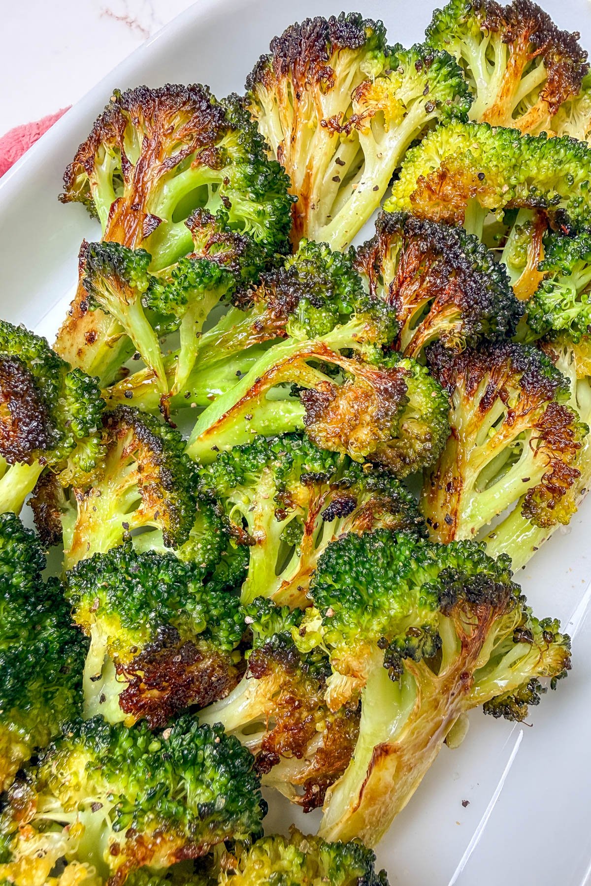 Oven roasted broccoli on a white platter.