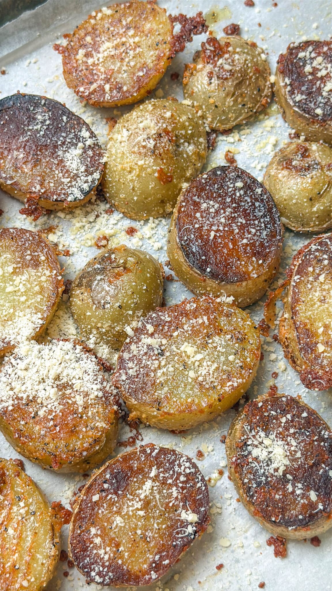 Potato slices flipped on the other side on a baking sheet with more of the parmesan cheese mixture on top.