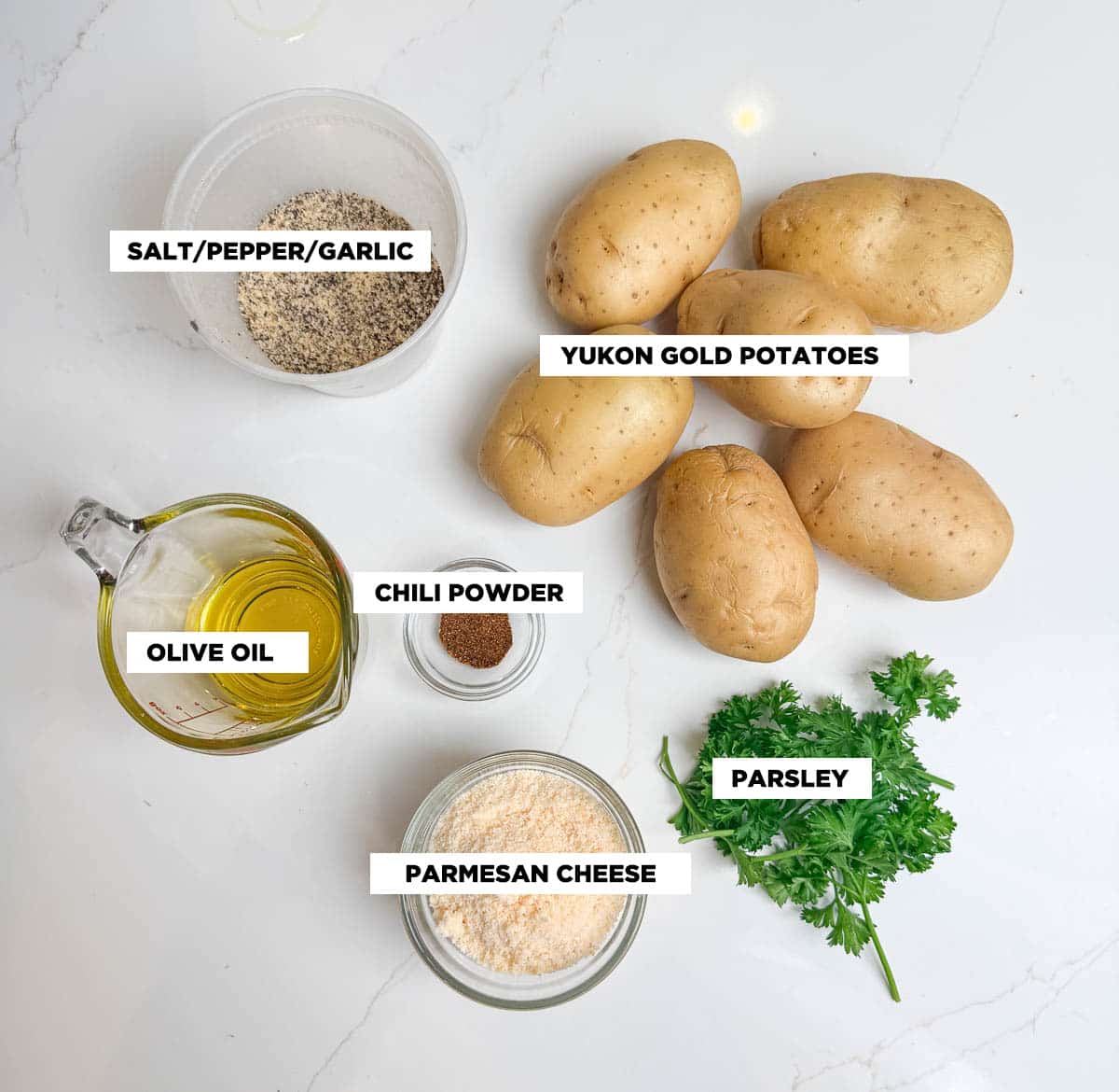 Ingredient shot for parmesan roasted potatoes, featuring: Yukon gold potatoes, olive oil, chili powder, parmesan cheese, parsley, and SPG.