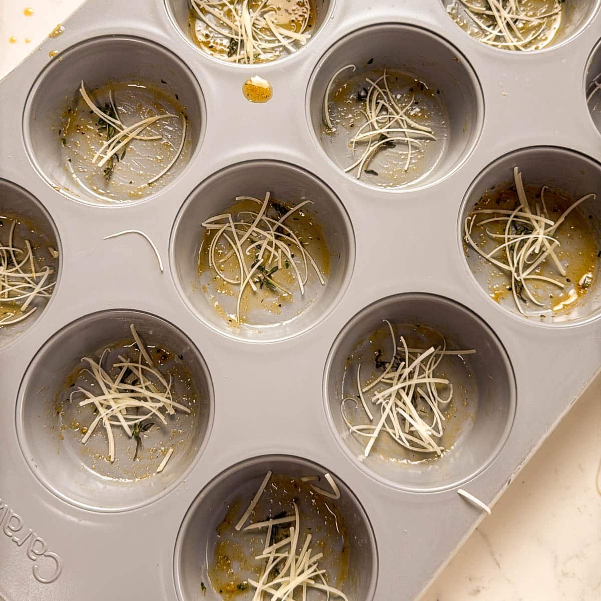 cupcake pans shot from above with sprigs of thyme and parmesan