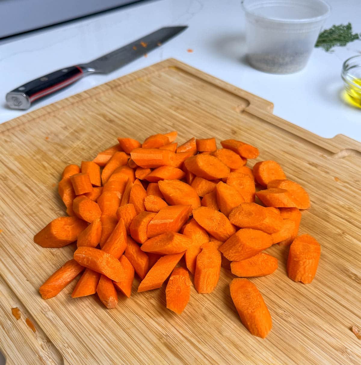 A pile of carrot pieces on a wooden cutting board.