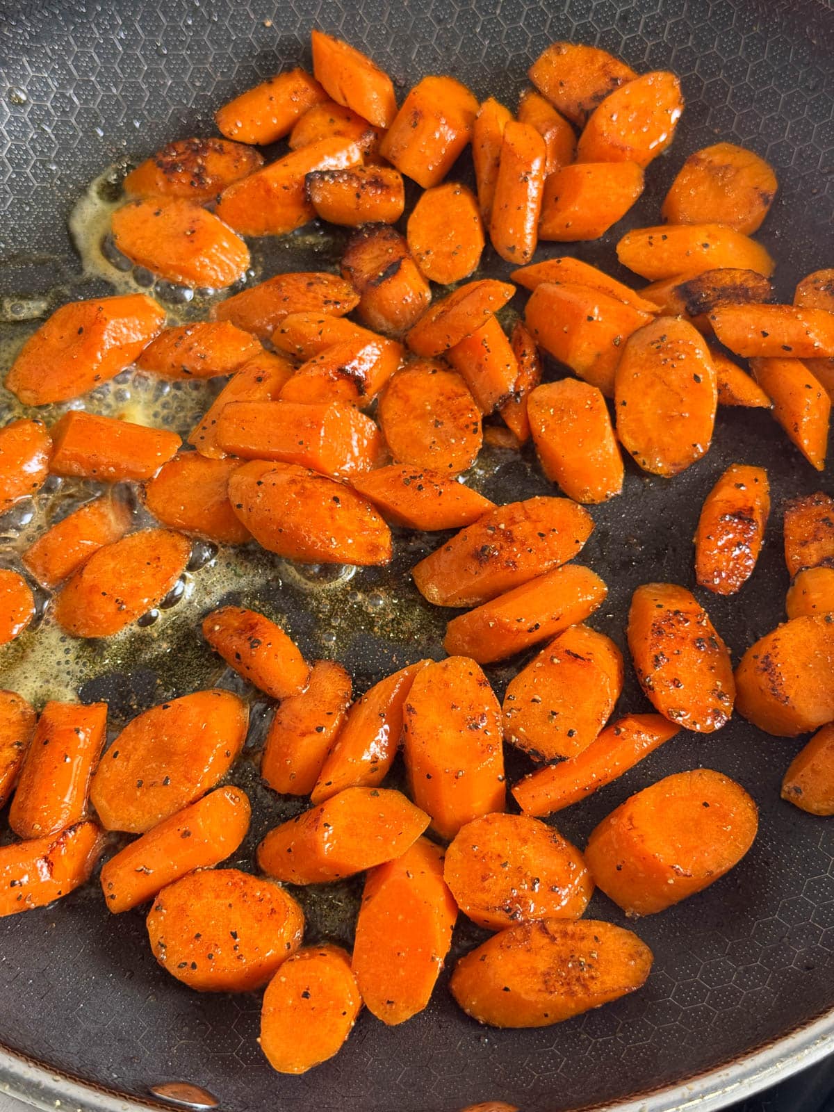 Carrots are seasoned and sautéing in the skillet.