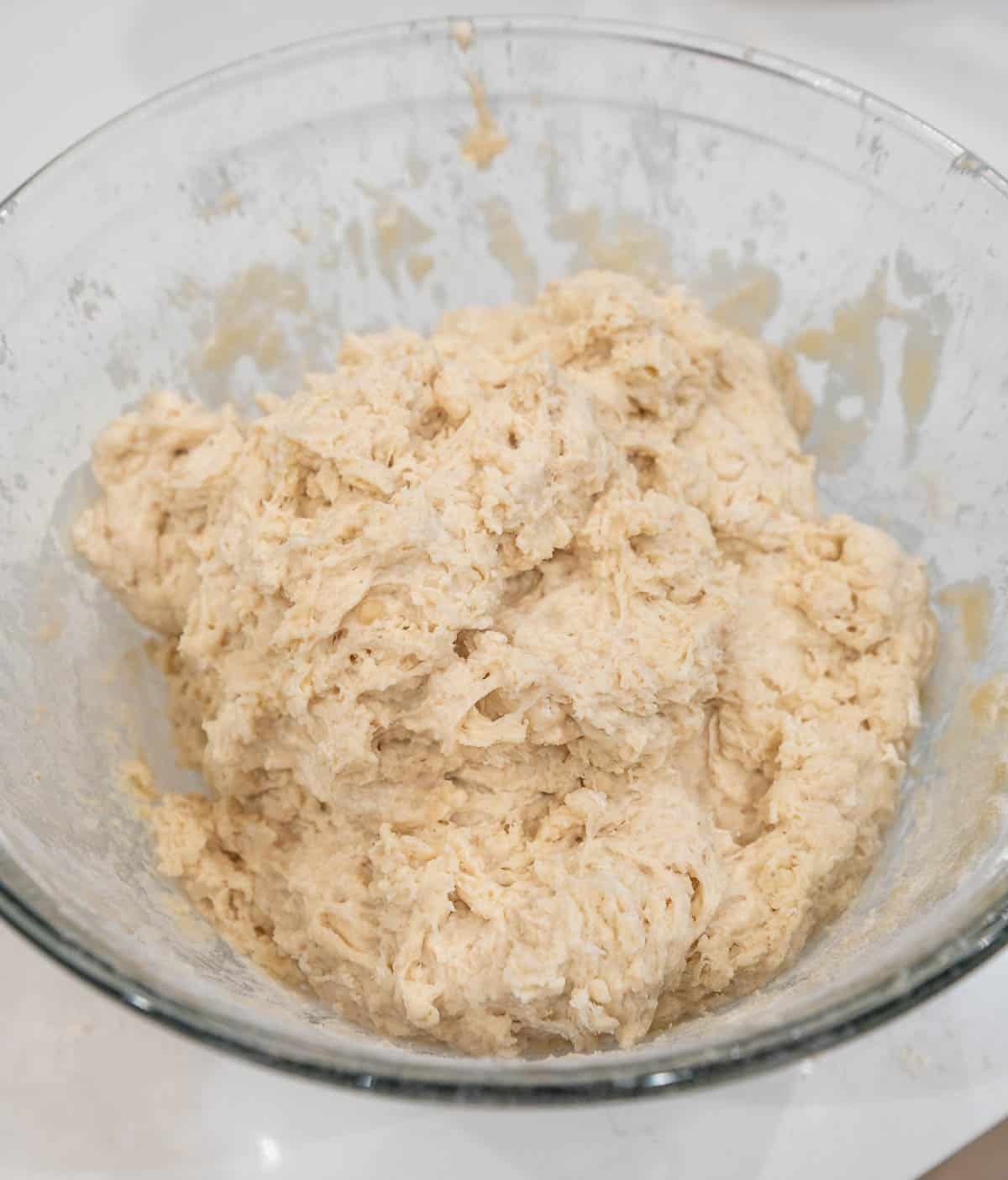 Rough looking sourdough dough in a glass bowl.